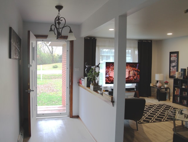 entrance foyer with wood-type flooring, a chandelier, and a healthy amount of sunlight