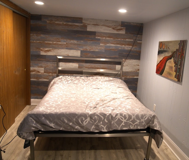 bedroom featuring hardwood / wood-style flooring and wooden walls