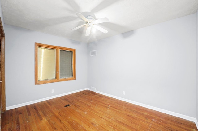 spare room featuring ceiling fan, hardwood / wood-style floors, visible vents, and baseboards