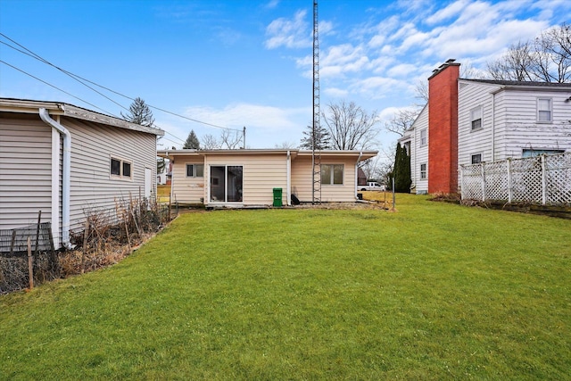 rear view of house with fence and a yard