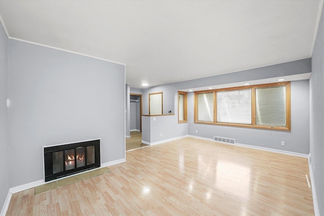 unfurnished living room featuring recessed lighting, wood finished floors, visible vents, baseboards, and a glass covered fireplace