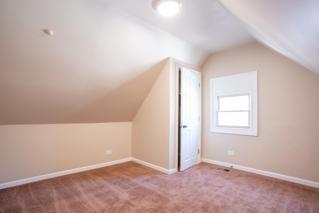 additional living space featuring baseboards, visible vents, vaulted ceiling, and carpet flooring