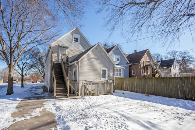 snow covered property featuring stairs, fence, and a residential view