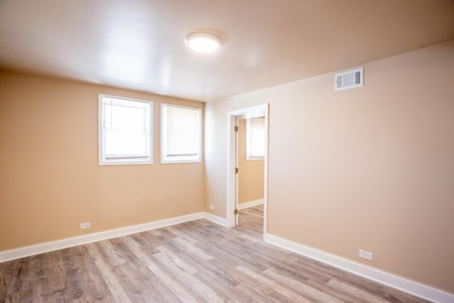 empty room with light wood-style flooring, visible vents, and baseboards