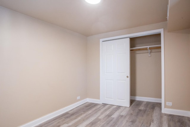 unfurnished bedroom with light wood-style floors, baseboards, and a closet