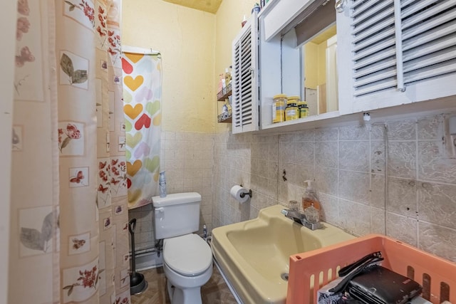 bathroom featuring toilet, a sink, and tile walls