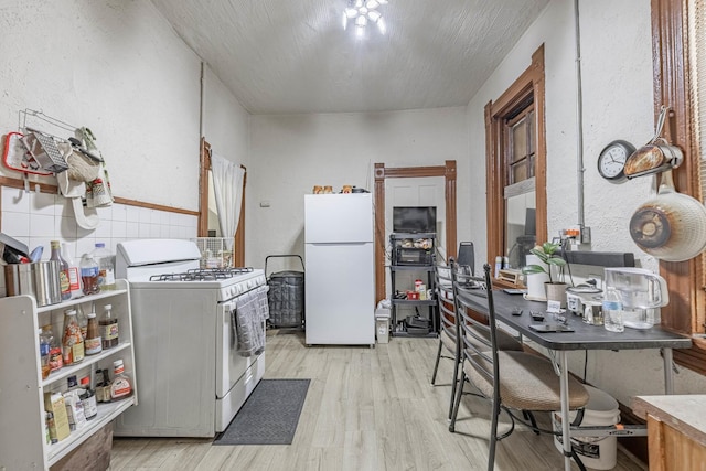 kitchen featuring a textured ceiling, white appliances, and light wood-style flooring