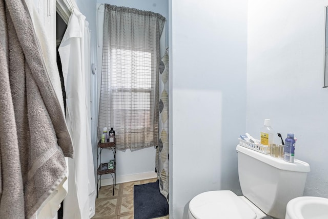 full bathroom with curtained shower, toilet, and baseboards