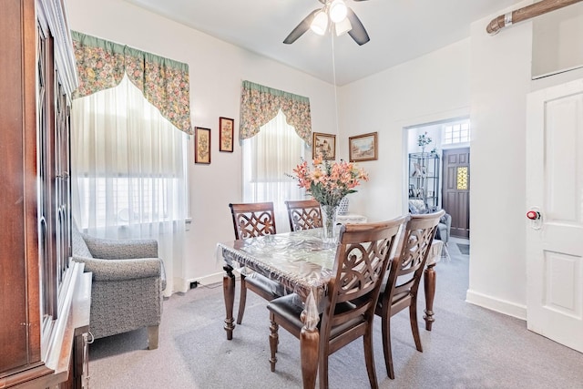 carpeted dining space featuring ceiling fan and baseboards