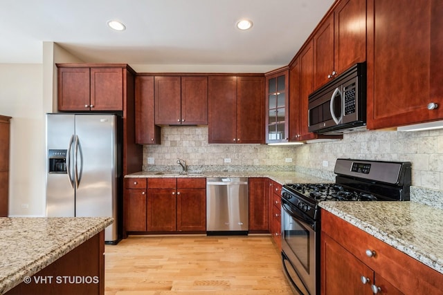 4953 Oakton St Unit 605, Skokie, IL 60077 - kitchen featuring appliances with stainless steel finishes, light stone countertops, light wood-style flooring, decorative backsplash, and recessed lighting
