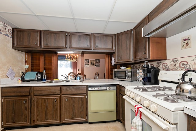 kitchen with wall chimney exhaust hood, sink, gas range gas stove, dark brown cabinets, and dishwasher