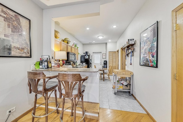 816 N Hermitage Ave, Chicago, IL 60622 - kitchen featuring black microwave, a breakfast bar area, a peninsula, baseboards, and recessed lighting