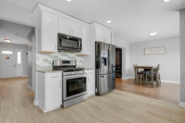 kitchen with backsplash, appliances with stainless steel finishes, light stone counters, and white cabinets