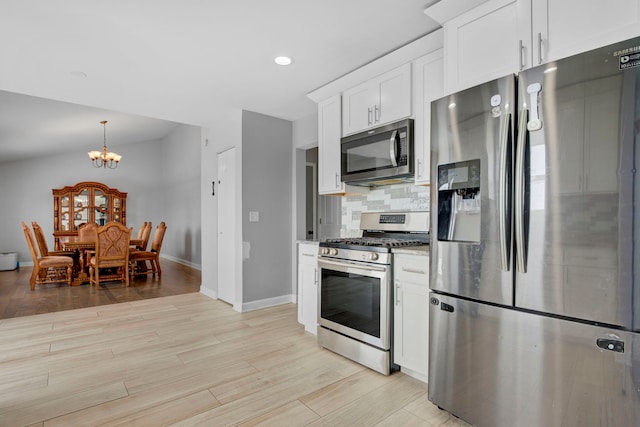 kitchen featuring an inviting chandelier, backsplash, stainless steel appliances, white cabinets, and light wood-type flooring