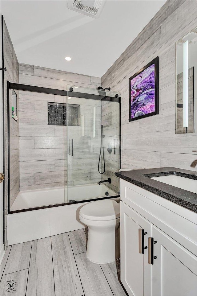 full bathroom featuring enclosed tub / shower combo, vanity, and toilet