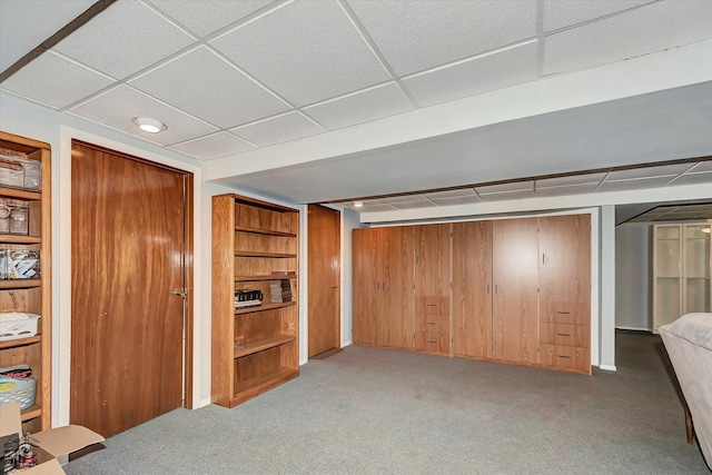 interior space featuring light colored carpet, wood walls, and a drop ceiling