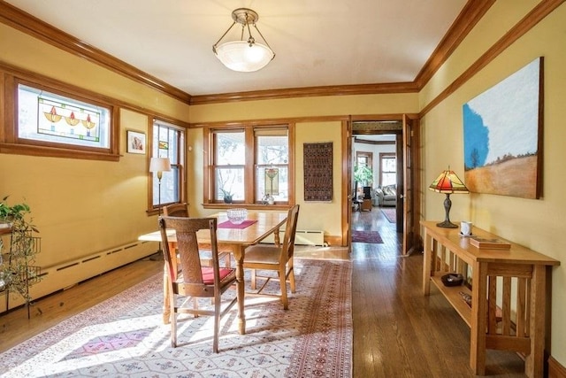 dining area with a baseboard heating unit, a baseboard radiator, crown molding, and wood finished floors