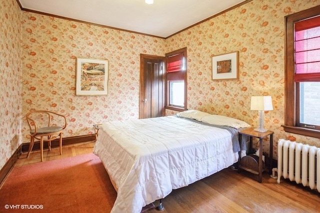 bedroom featuring baseboards, radiator heating unit, wood finished floors, and wallpapered walls