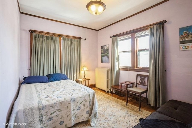 bedroom featuring crown molding, radiator heating unit, and light wood-style floors