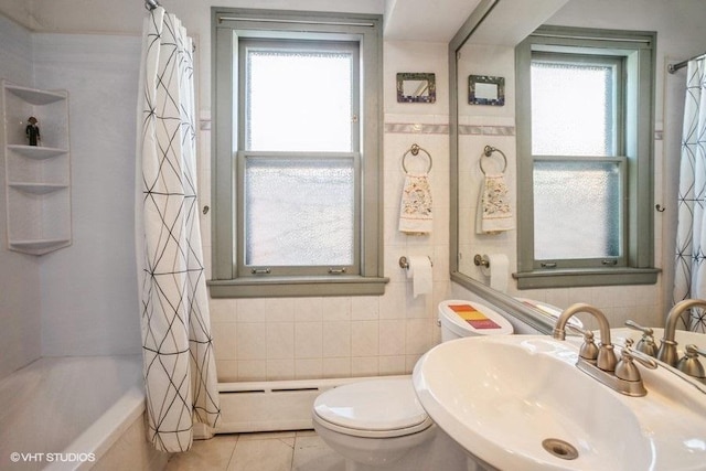 bathroom with toilet, tile patterned floors, a sink, a baseboard heating unit, and tile walls