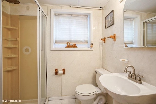 bathroom with tile walls, a sink, a shower stall, and toilet