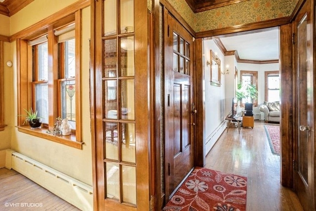 corridor featuring a baseboard heating unit, wood finished floors, and ornamental molding