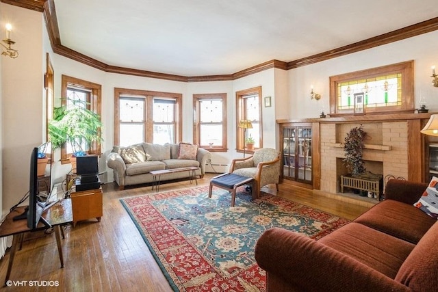 living room featuring baseboard heating, wood-type flooring, a fireplace, and crown molding