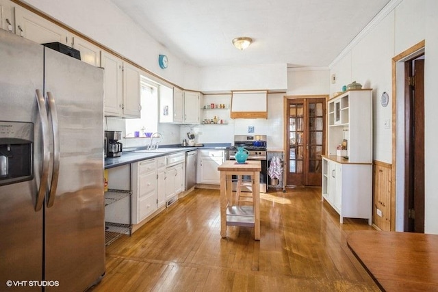 kitchen featuring open shelves, stainless steel appliances, white cabinetry, a sink, and hardwood / wood-style flooring