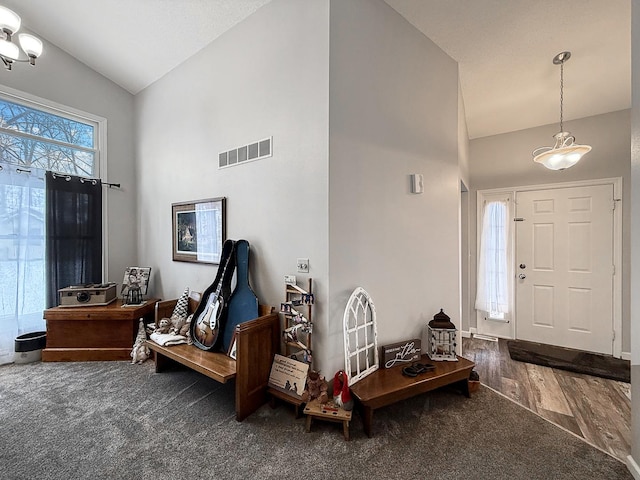 carpeted entrance foyer featuring visible vents, vaulted ceiling, and wood finished floors