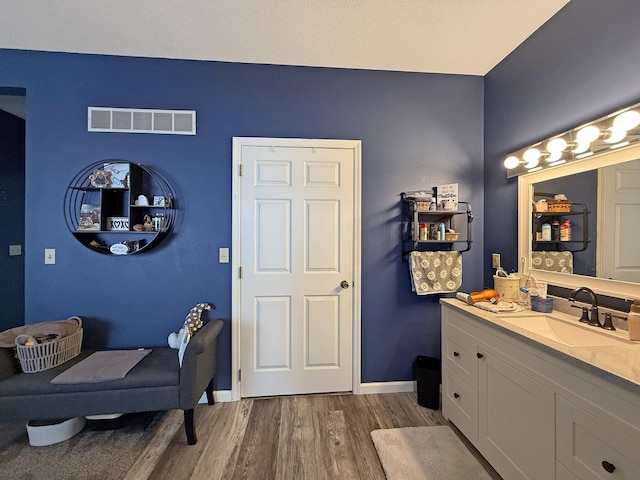 bathroom featuring baseboards, visible vents, wood finished floors, and vanity