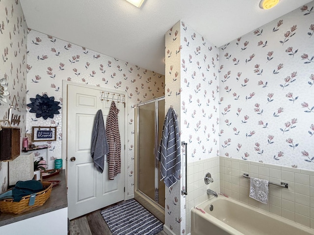 full bath with a garden tub, a shower stall, a textured ceiling, wood finished floors, and wallpapered walls