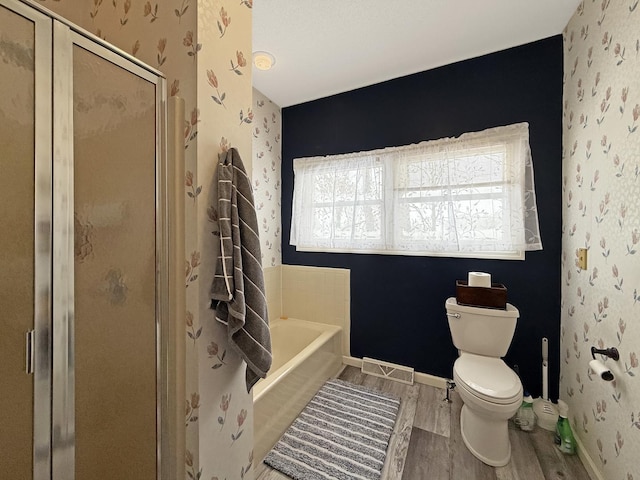 full bathroom featuring toilet, wallpapered walls, a shower stall, and wood finished floors