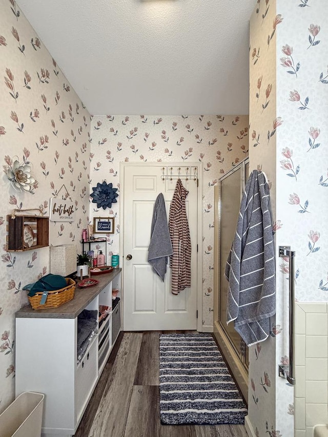 mudroom with dark wood-style floors, a textured ceiling, and wallpapered walls