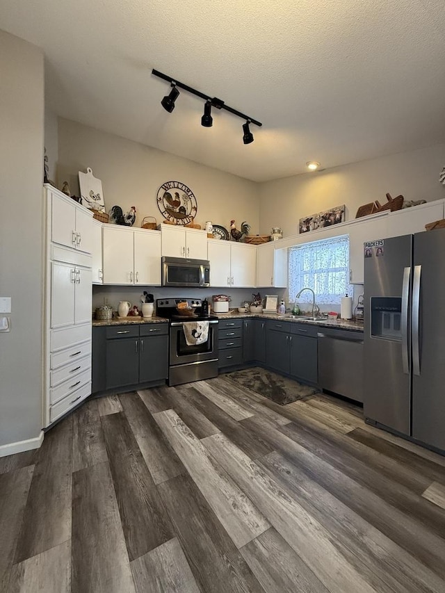 kitchen featuring a sink, white cabinetry, stainless steel appliances, and dark wood finished floors