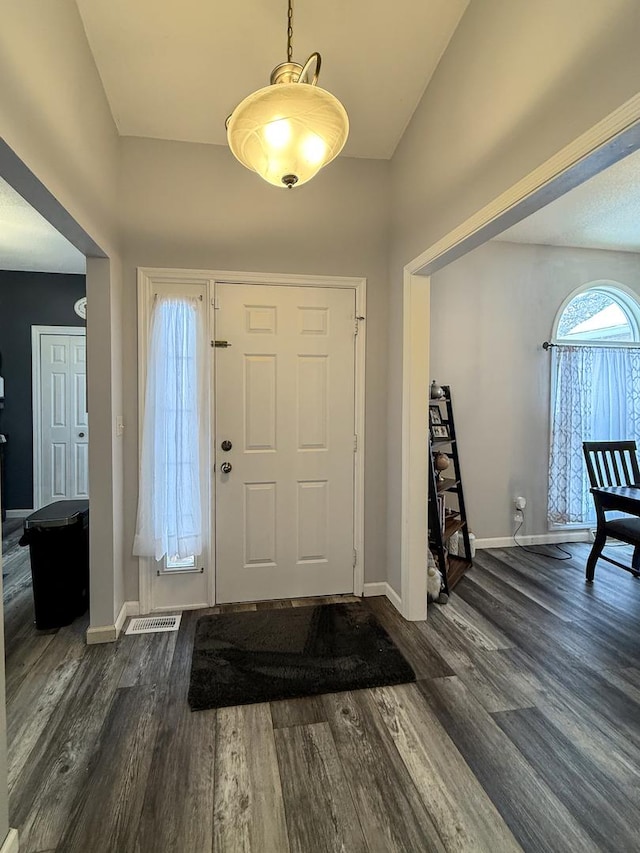 foyer with lofted ceiling, dark wood-style flooring, and baseboards