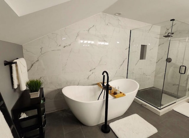 bathroom with shower with separate bathtub, vaulted ceiling, and tile walls