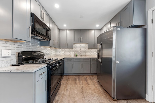 kitchen featuring light stone counters, gray cabinets, sink, and black appliances