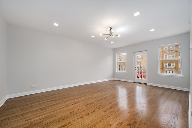 spare room featuring hardwood / wood-style flooring and a chandelier