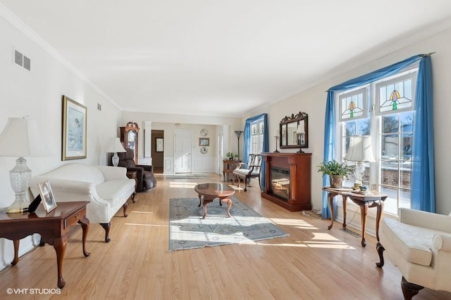 living room featuring crown molding and light hardwood / wood-style flooring