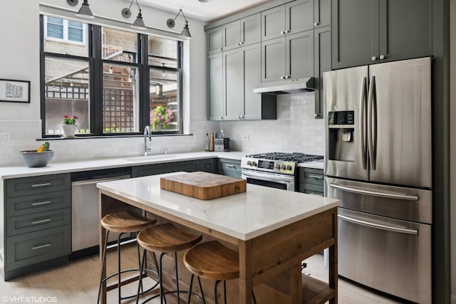 kitchen with sink, tasteful backsplash, a center island, stainless steel appliances, and light stone countertops