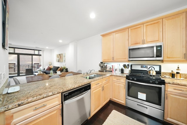 kitchen with appliances with stainless steel finishes, light brown cabinetry, sink, and kitchen peninsula