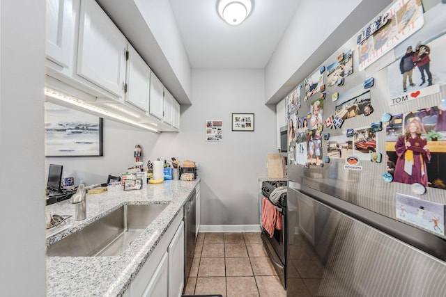 kitchen featuring appliances with stainless steel finishes, sink, white cabinets, light tile patterned floors, and light stone countertops