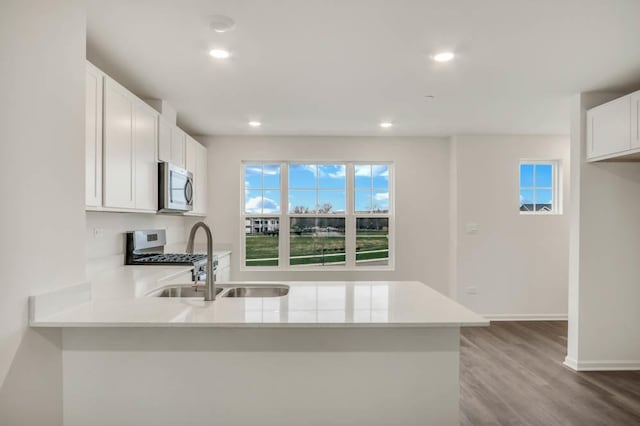 kitchen with appliances with stainless steel finishes, sink, white cabinets, and kitchen peninsula