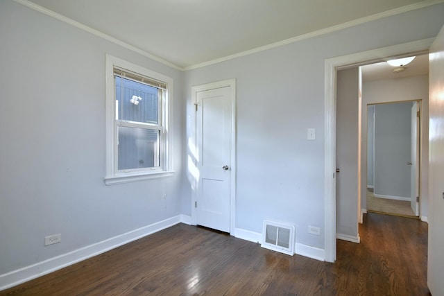 unfurnished bedroom with dark wood-type flooring, ornamental molding, and a closet