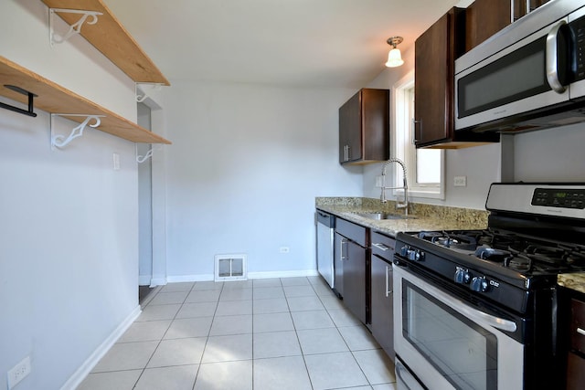 kitchen with light stone counters, dark brown cabinetry, appliances with stainless steel finishes, and sink