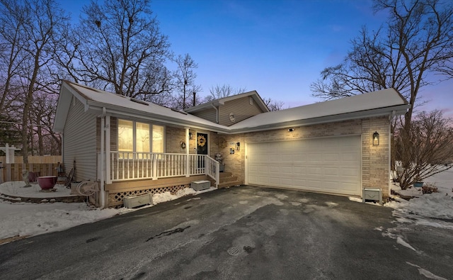 ranch-style home with a garage, fence, aphalt driveway, and brick siding