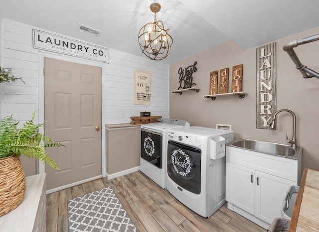 washroom featuring cabinet space, visible vents, light wood-style floors, a sink, and separate washer and dryer