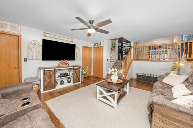 living area featuring stairway, wood finished floors, and a ceiling fan