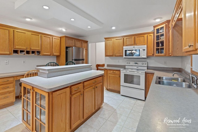 kitchen with sink, a center island, built in desk, light tile patterned floors, and white appliances