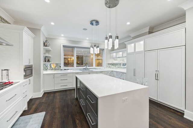 kitchen with hanging light fixtures, a center island, tasteful backsplash, ornamental molding, and white cabinets